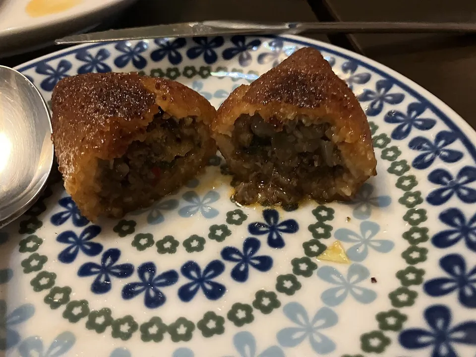 キベの実写写真（レバントの挽き割り小麦（ブルグル）＋挽肉の紡錘形コロッケ（揚げキベ/kubba）。半分に切って外殻と挽肉フィリングの断面を見せた完成皿。）