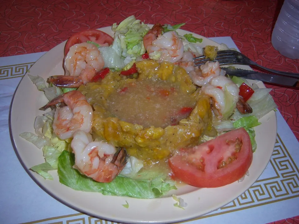モフォンゴの実写写真（プエルトリコ・サンフアンの店の完成皿。潰し揚げプランテンの山にエビ添え（mofongo con camarones）＝現行代表形。CC0）
